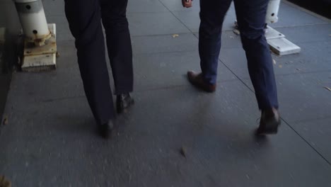 Shot-of-two-men-in-suits-from-the-waist-down-walking-down-a-city-street