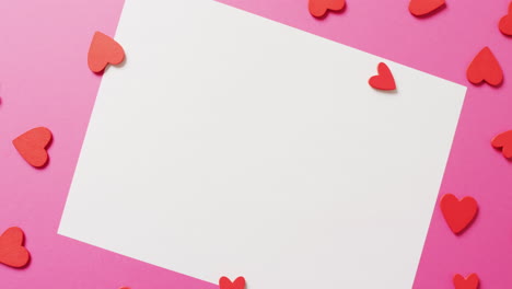 video de formas de corazón de papel rojo y hoja de papel blanca y negra con espacio para copiar, sobre fondo rosa.