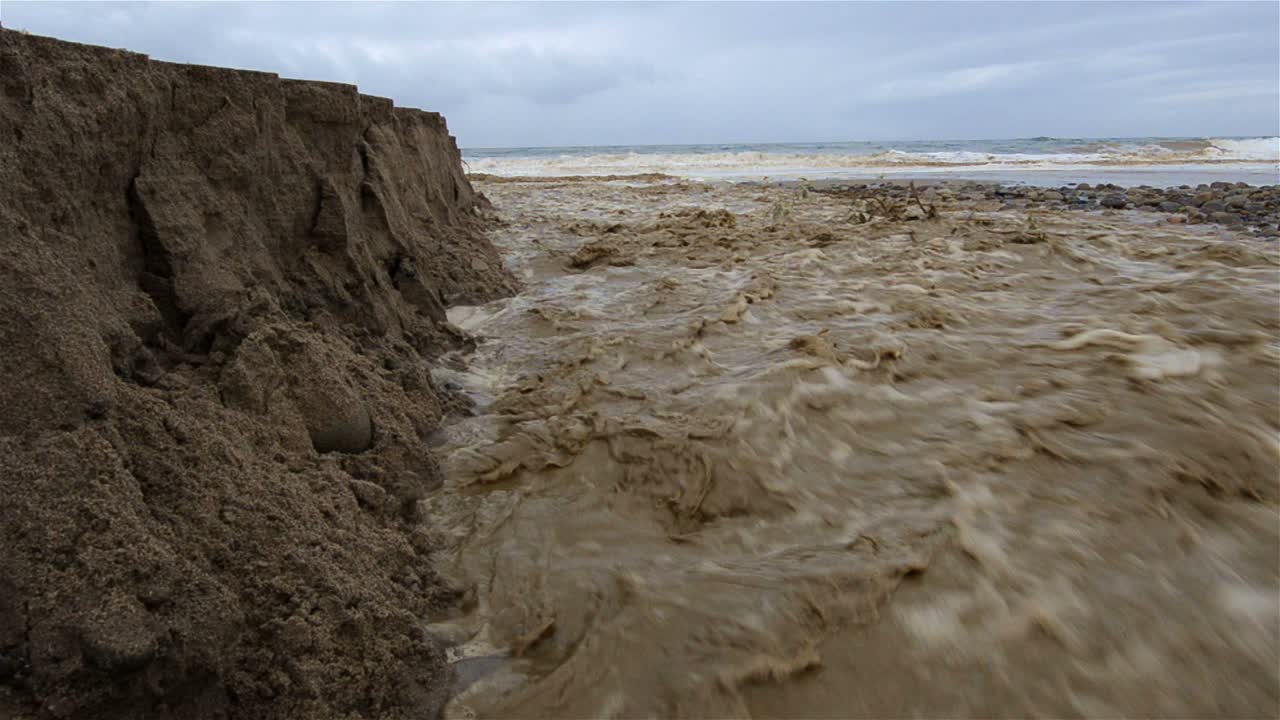 Low angle of Sanjon Creek washing beach sand into the ocean after heavy rain in Ventura California