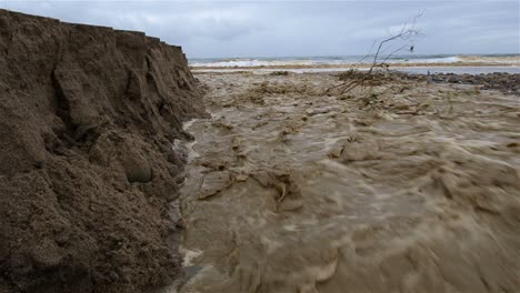 Niedriger-Winkel-Des-Sanjon-Creek,-Der-Nach-Starkem-Regen-In-Ventura-Kalifornien-Strandsand-In-Den-Ozean-Spült