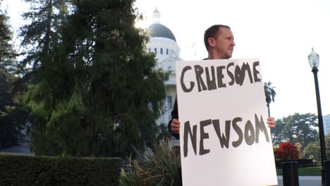 male political protester with gruesome newsom sign