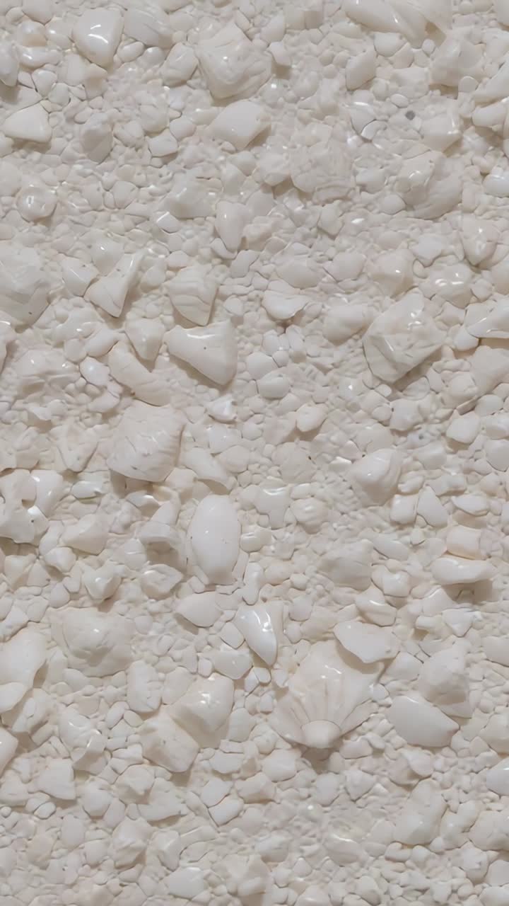 Video verticale: camera con movimento panoramico che riprende la superficie di una stanza, riflessi che si spostano su frammenti di conchiglia nella malta