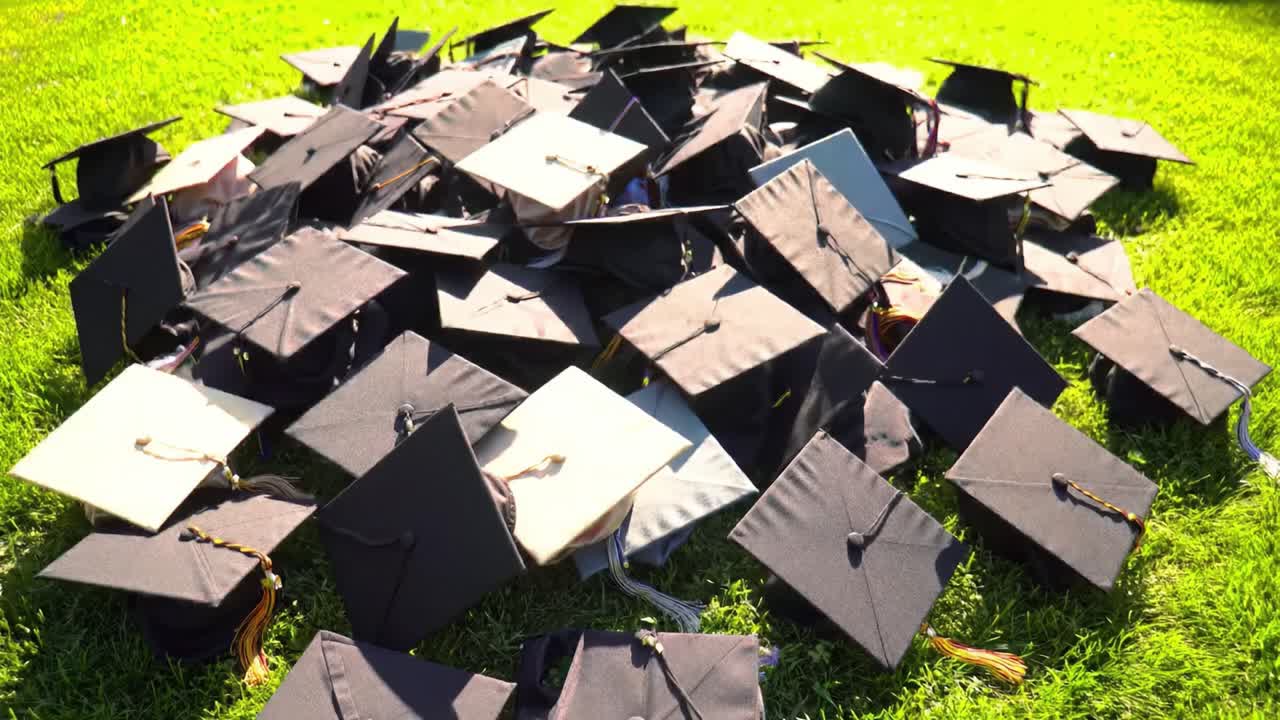 A joyful display of numerous graduation caps scattered across vibrant green grass, symbolizing academic success. This celebration reflects the culmination of hard work and dedication.