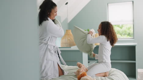 mother, child and smile for pillow fight on bed