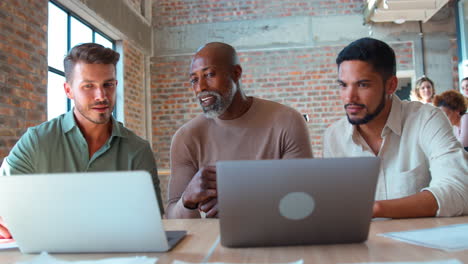 male multi-cultural business team meeting around laptop in office