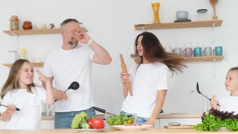 Happy family dancing and having fun while cooking in the kitchen