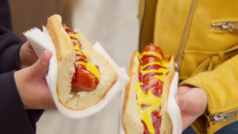 close up of two women buying hot dogs from street food market stall 2