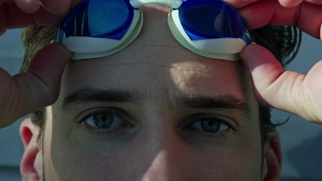 primer plano de un nadador masculino poniéndose las gafas de natación