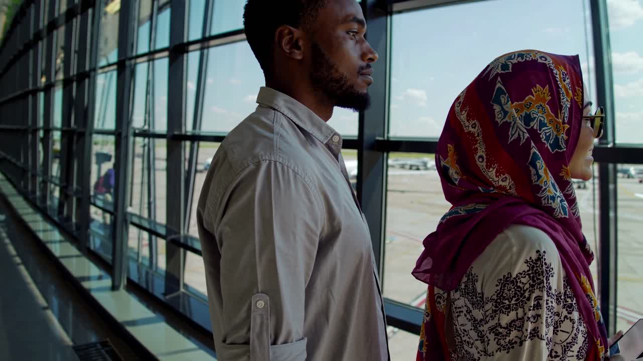 Vista laterale di un uomo e una donna in un moderno terminal aeroportuale, che cattura un momento di viaggio spontaneo
