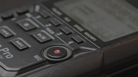 Finger-pressing-the-record-button-of-a-digital-audiorecorder---close-up