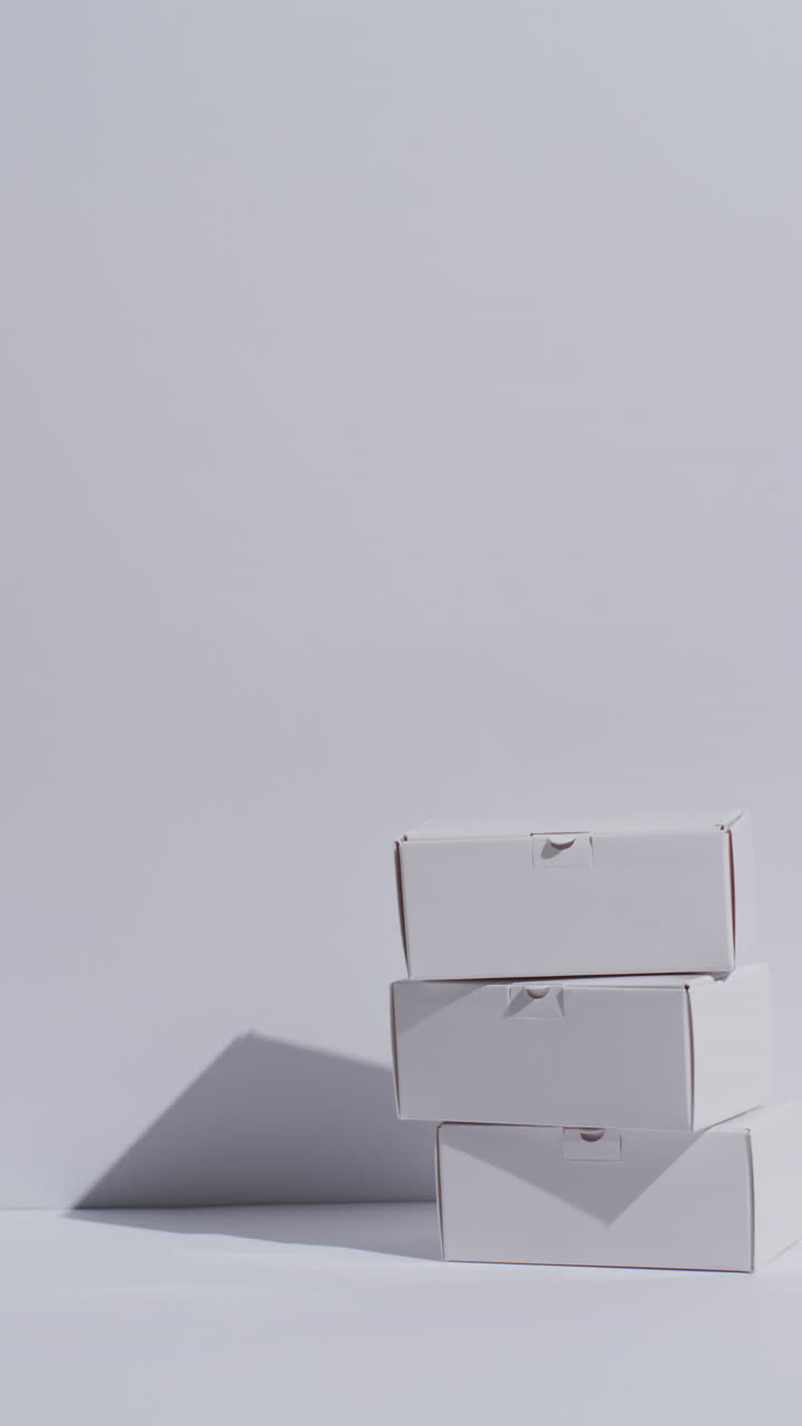 Vertical video of stacked cardboard boxes with copy space over white background