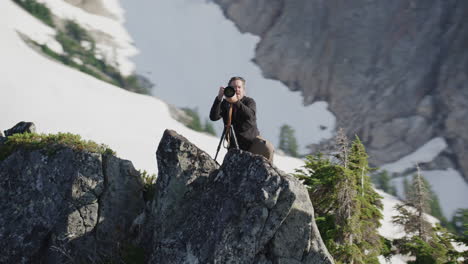 el fotógrafo gira con la cámara sobre un trípode en la cresta de la montaña alpina, el helicóptero de seguimiento medio de tim durkan en sentido contrario a las agujas del reloj orbita a cámara lenta