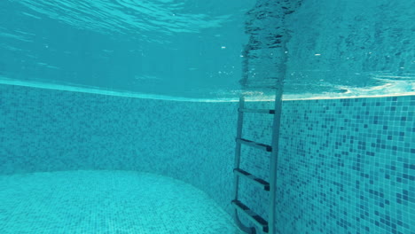 un joven nada bajo el agua en una piscina.
