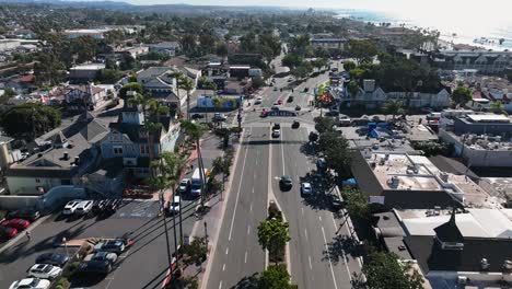 Aerial-drone-shot-over-pacific-coast-highway-going-through-the-town-of-Carlsbad-California,-USA-beside-the-sandy-beach-on-a-town-landscape