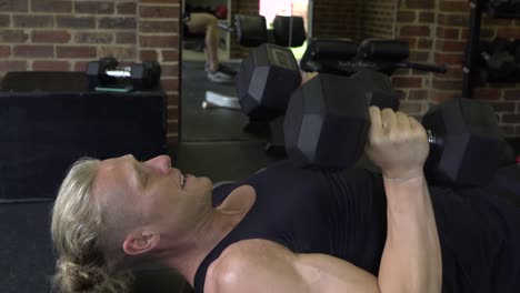 Muscly-man-in-home-gym-exercising-close-grip-dumbbell-bench-tricep-press-shot-from-side