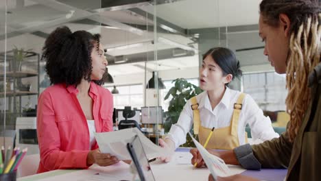 busy diverse business creatives at table discussing work in casual office meeting, in slow motion