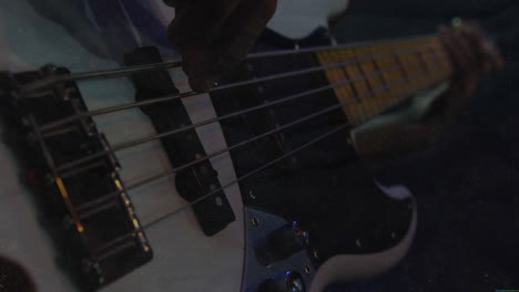 bassist plucking metal strings under moody stage lighting, with animated eq bars and music data