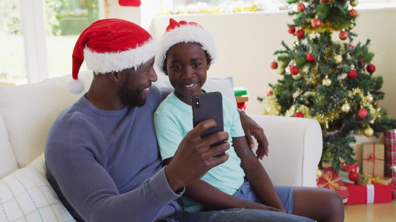 African american father and son having a videocall on smartphone