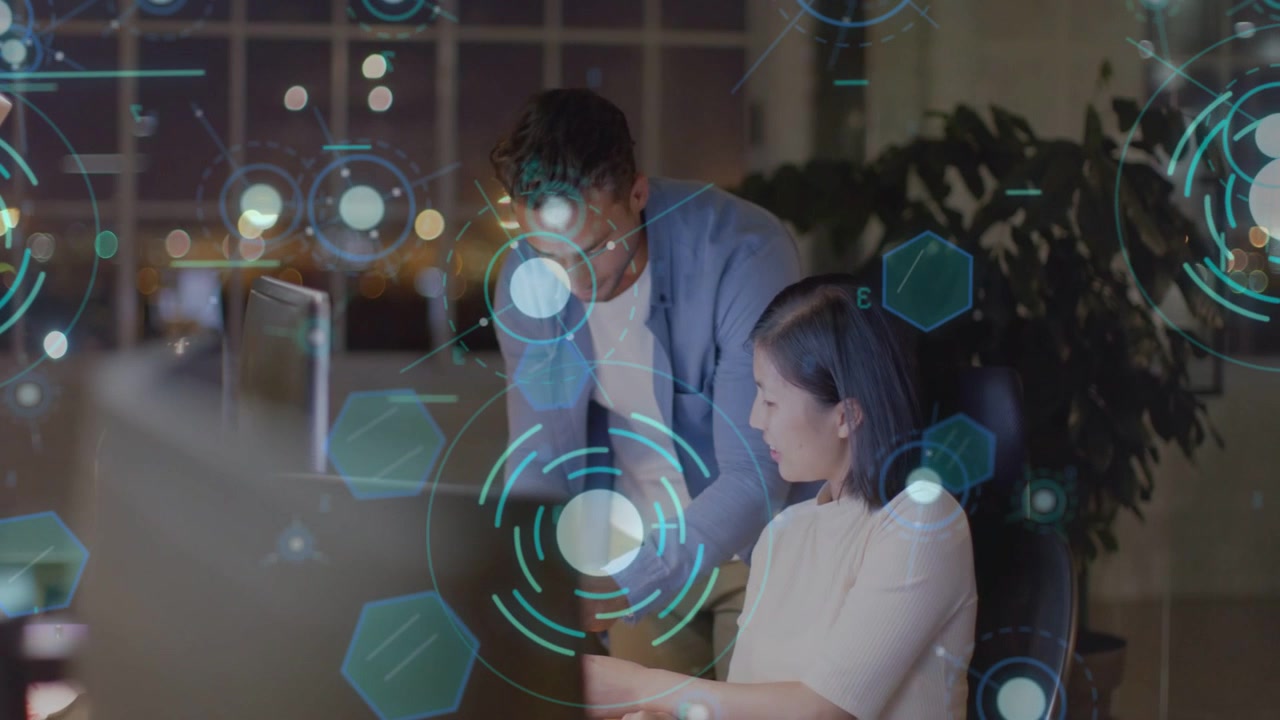 Man leaning and pointing at monitor, tech holographic UI guiding woman editing design for review