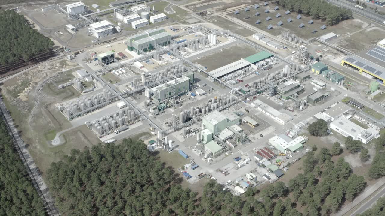 High drone shot providing wide overview of large industrial factory zone, including solar panels and forest, Castets, France