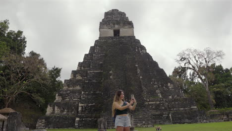 tourist woman takes selfie in tikal pyramid, guatemala. social media travel photos. millennial. slow motion