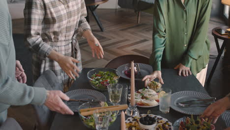 familia irreconocible parada cerca de la mesa en la sala de estar y lista para comer juntos