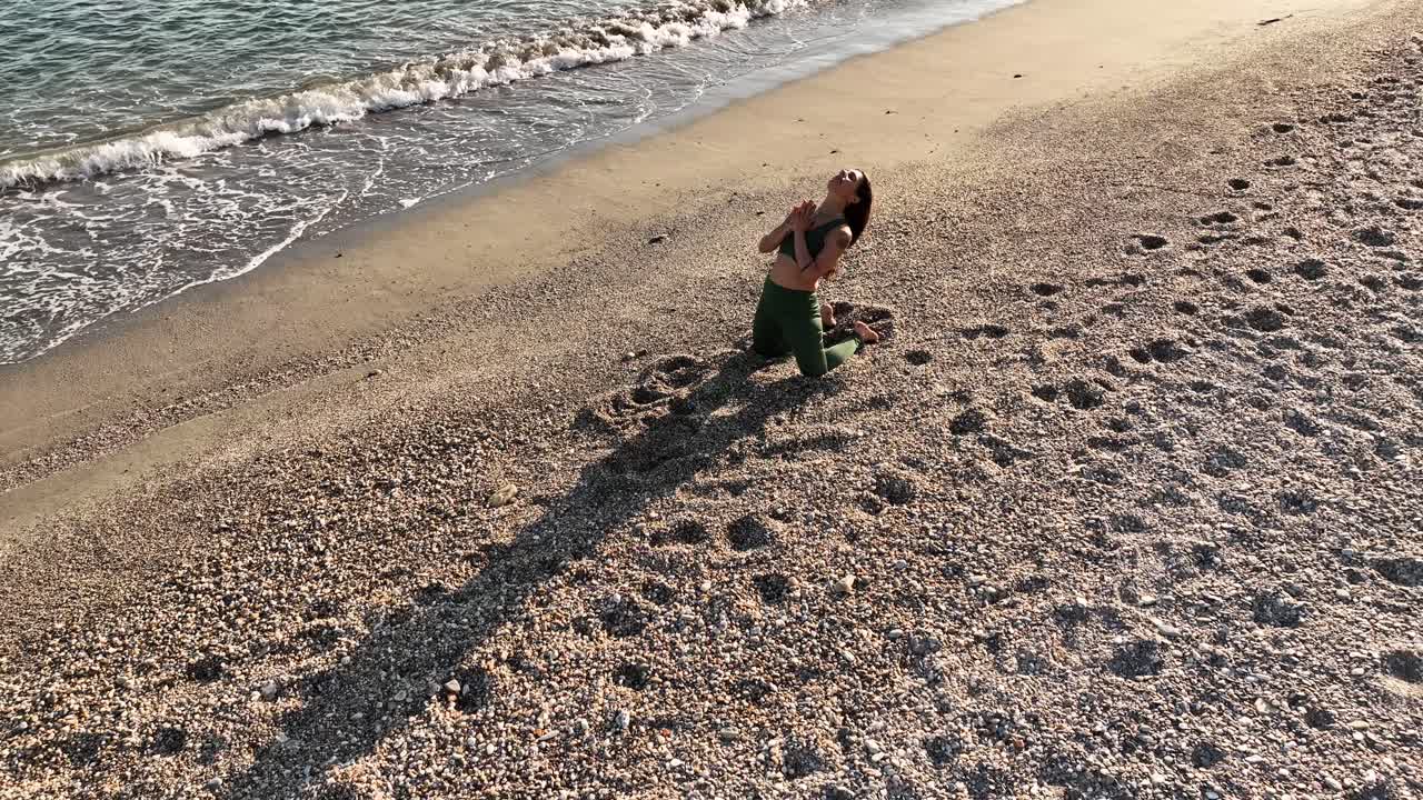 Young woman performing camel pose variation on the beach