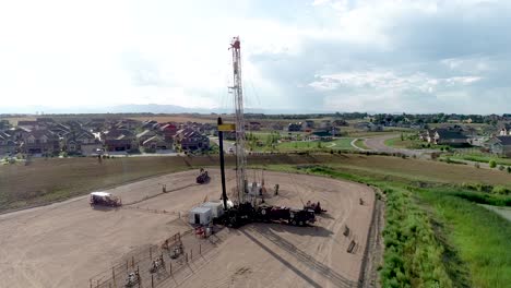 a drone shot of an oil well extraordinarily close to a wealthy fancy neighborhood