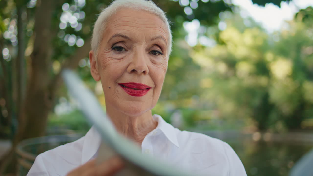 Portrait smiling senior reading news magazine in park. Happy mature model posing