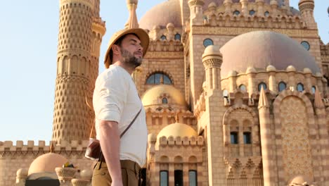a tourist stands with a camera near the mosque