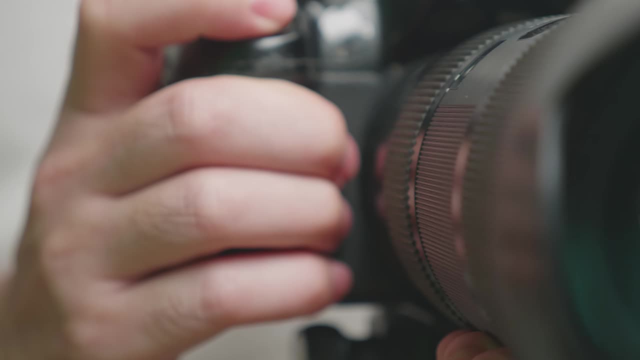Lähikuva käsistä, jotka pitävät kameraa ja tarkentavat objektiivia valokuvausta tai videointia varten.