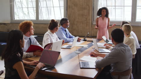 black female boss stands instructing colleagues at a meeting