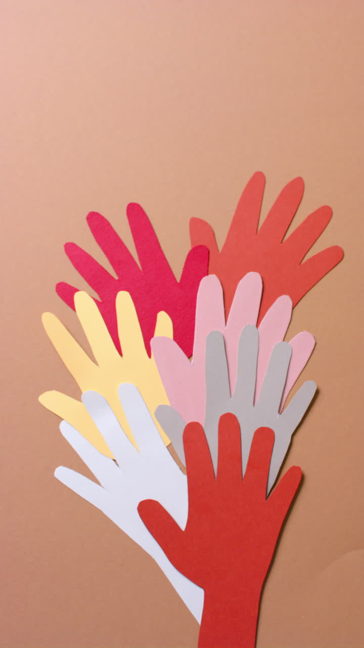 Vertical video of hands together made of colourful paper on brown background with copy space