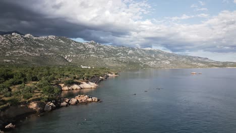 Wunderschöne-Steinküste-Eines-Ozeans-Mit-Großen-Bergen-Im-Hintergrund-Zur-Goldon-Stunde