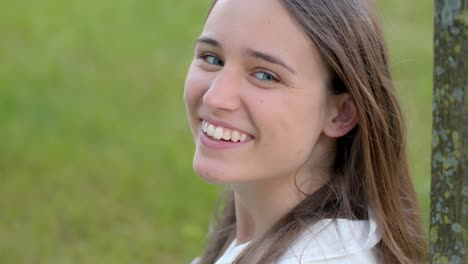 Happy-young-woman-smiling-and-looking-into-camera,-green-background