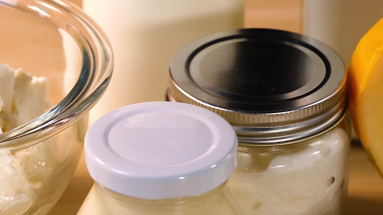 A variety of cheeses and sealed jars arranged on a light wooden surface.
