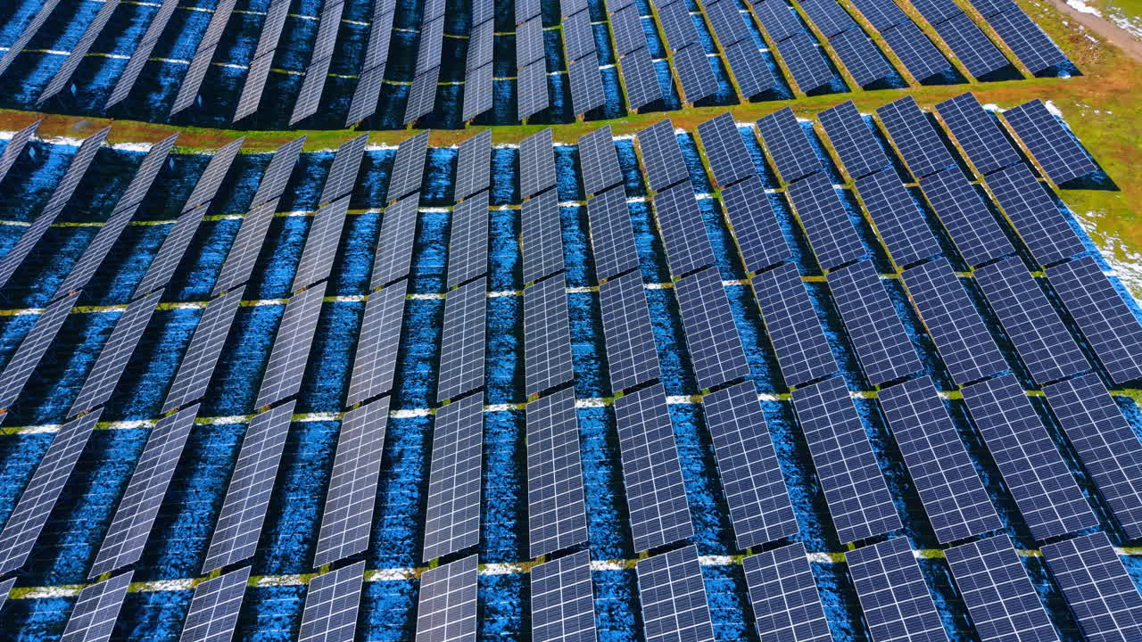 Vista aerea di file di pannelli solari su campo invernale. Vista dall'alto di pannelli fotovoltaici disposti in file con leggera neve sul terreno tra di essi