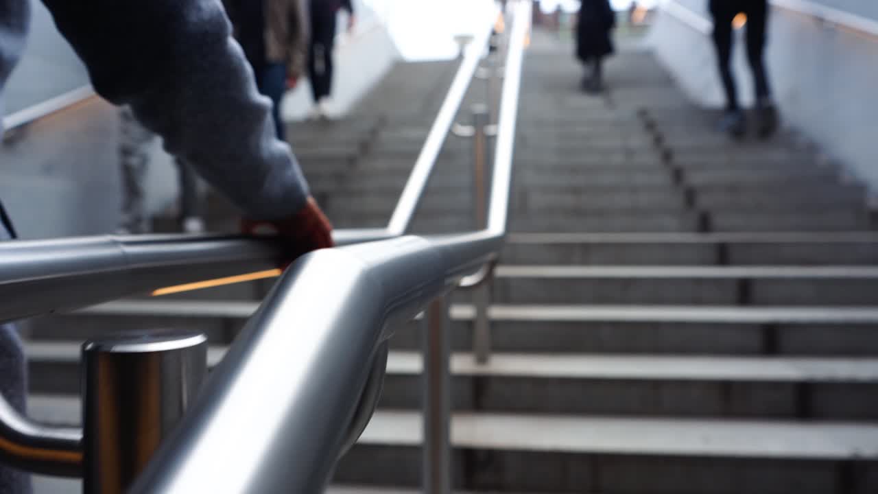 Caucasian man walking up stairs with hand on stainless steel railing