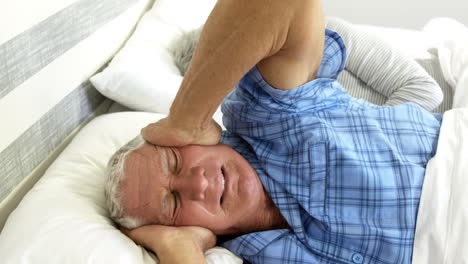 senior man covering her ears while woman snoring
