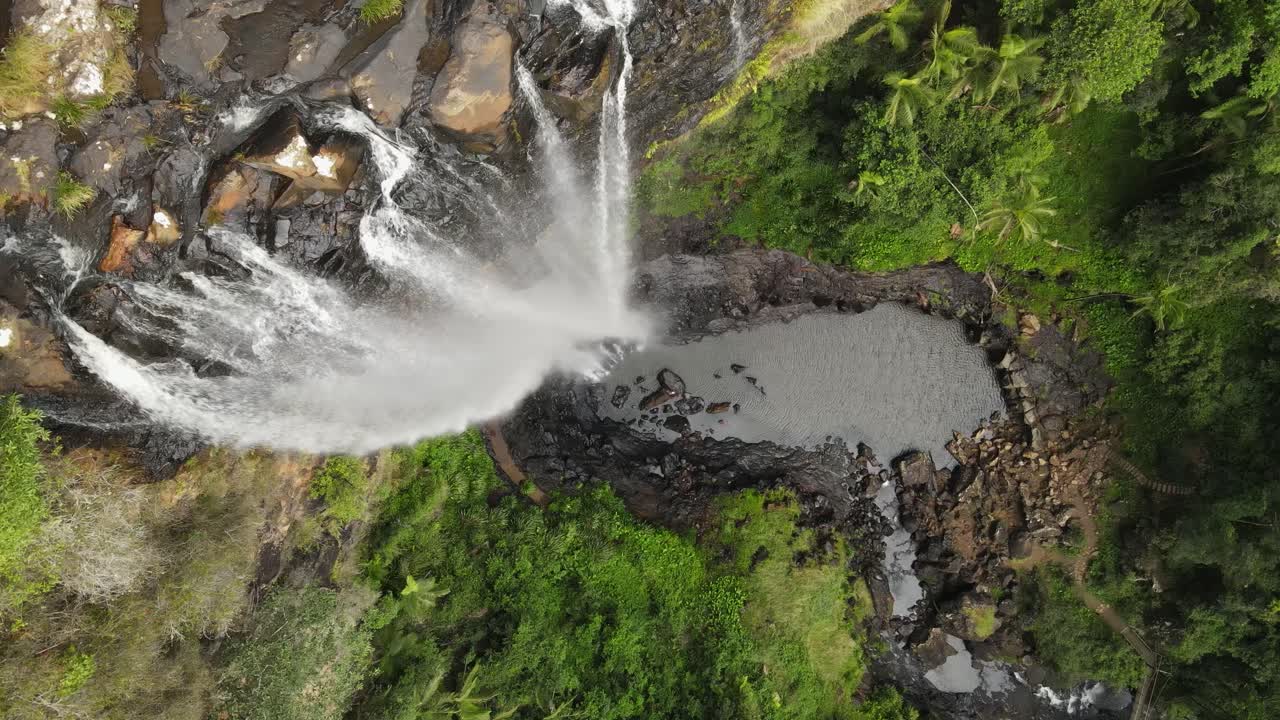 agua en cascada sobre un acantilado escarpado en un agujero de natación natural en lo profundo de una escena de selva tropical