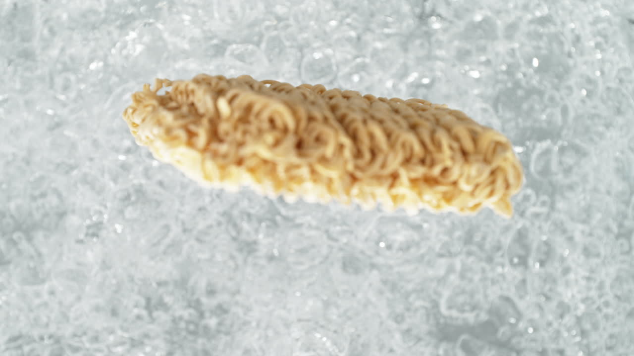 fideos cayendo en una olla de agua hirviendo haciendo un salto en cámara lenta, vista de la mesa