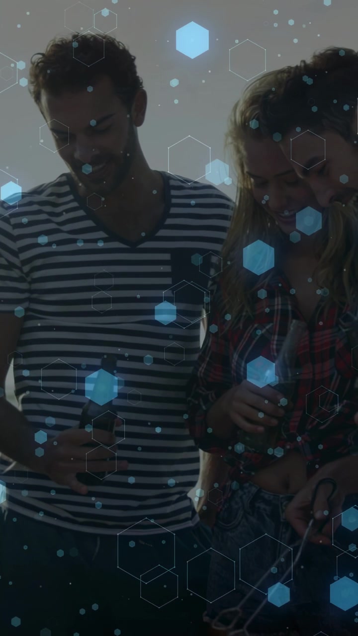 Vertical video: Friends leaning to check food as person flipping at grill, blue hexes over hands