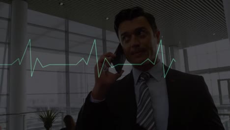 Animation-of-moving-heart-rhythm-over-caucasian-businessman-talking-on-cellphone-at-office