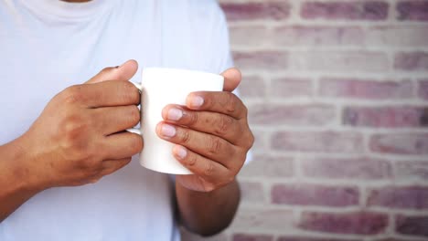 persona que sostiene una taza blanca