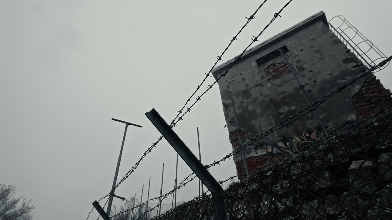 Dilapidated Concrete Guard Tower Behind Barbed Wire Fence