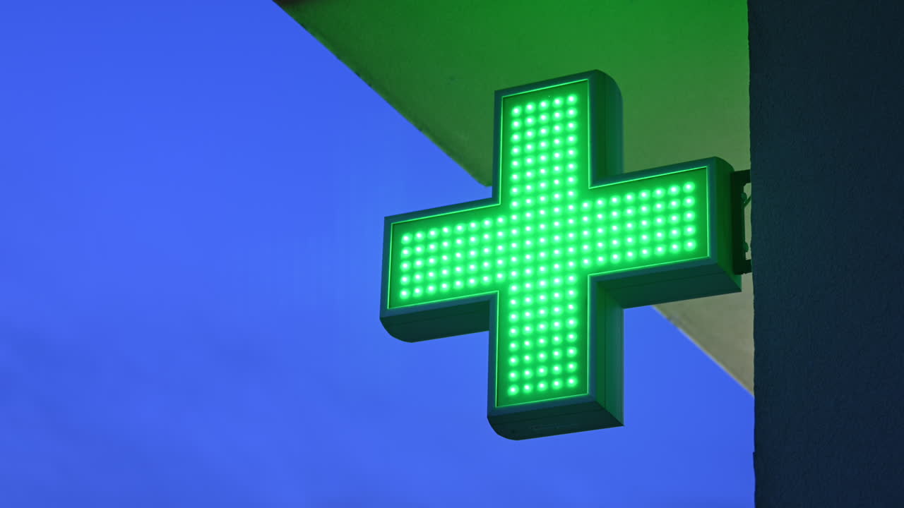 Pharmacy store green cross blinking at night