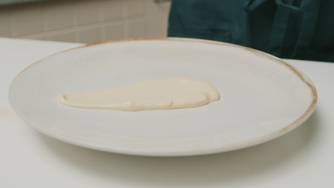 Placing homemade mayonnaise onto big plate on kitchen table