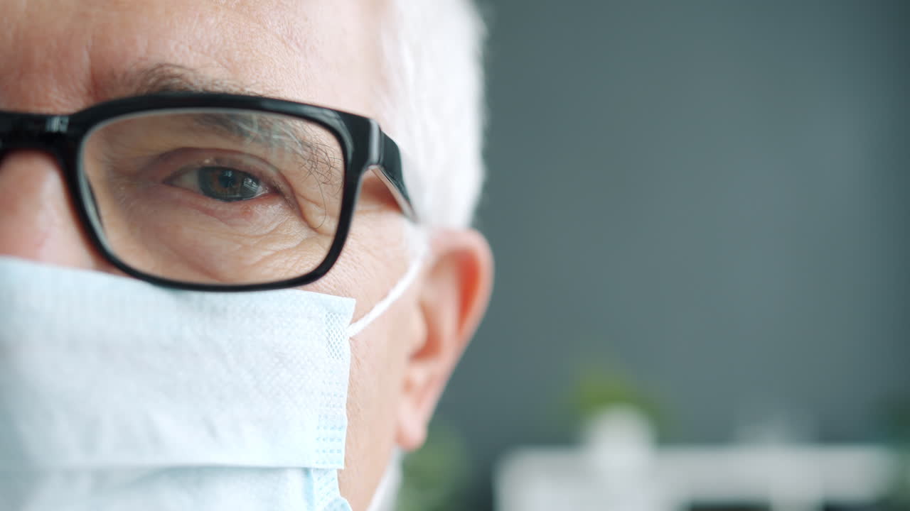 Close-up of a senior man wearing glasses and a face mask