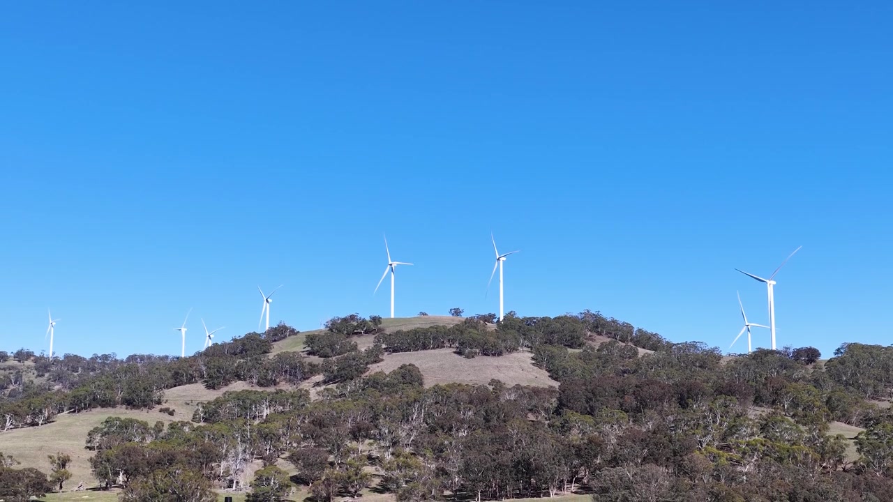 Inquadratura ampia di turbine eoliche che generano energia rinnovabile su una collina rurale australiana a Matheson