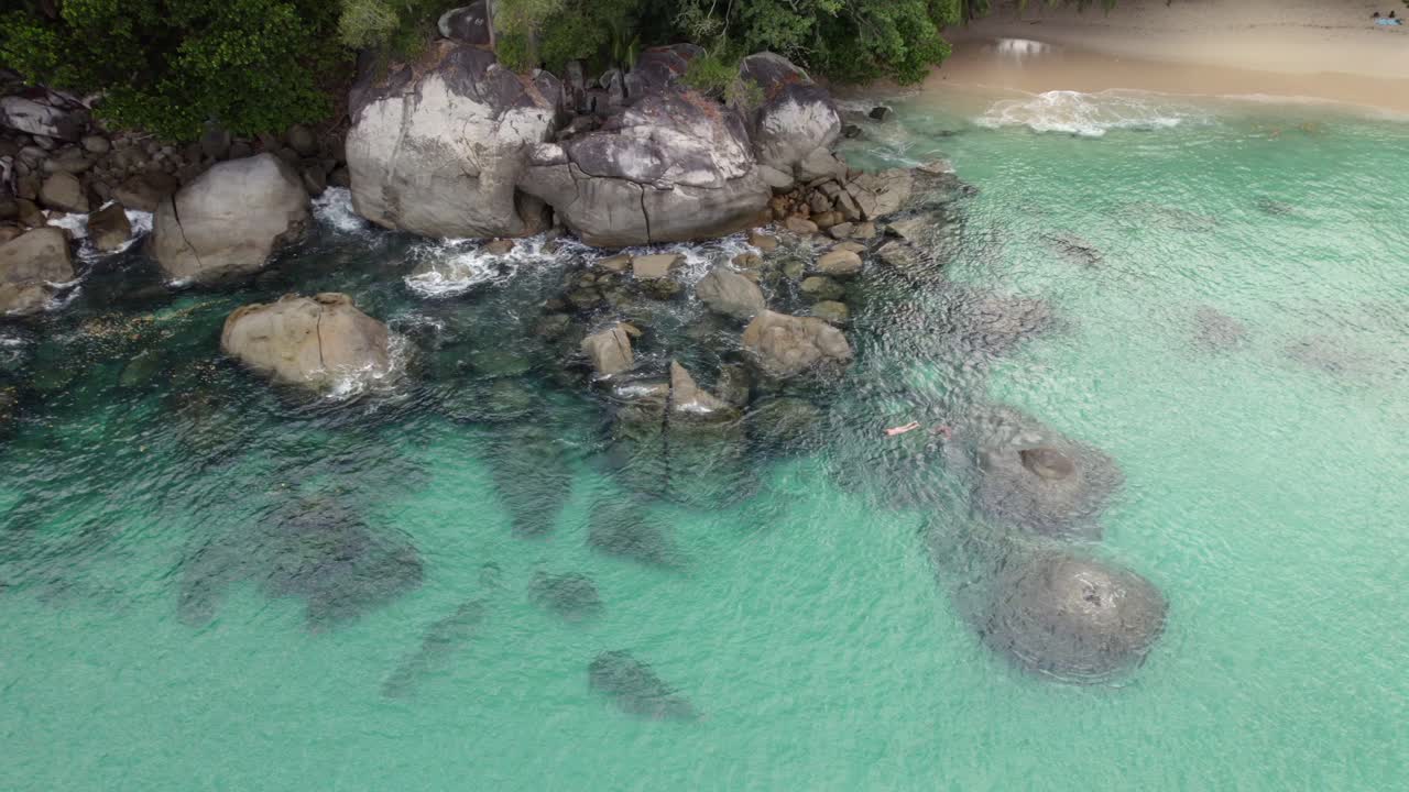 Filmato aereo di Drone della spiaggia di Sunset sull'isola di Mahe, coppia di turisti che fanno snorkeling vicino alle rocce, acqua cristallina, Mahe Seychelles 30fps 001